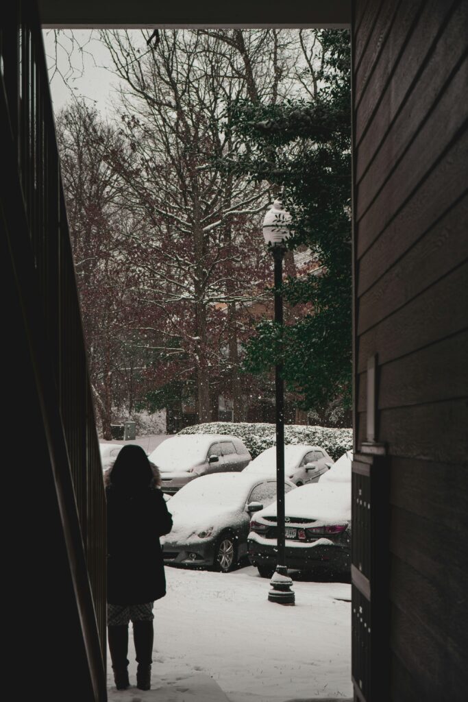 person standing in doorway isolated looking at cars covered in snow
