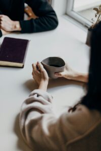 Person sitting at table with coffee with another person