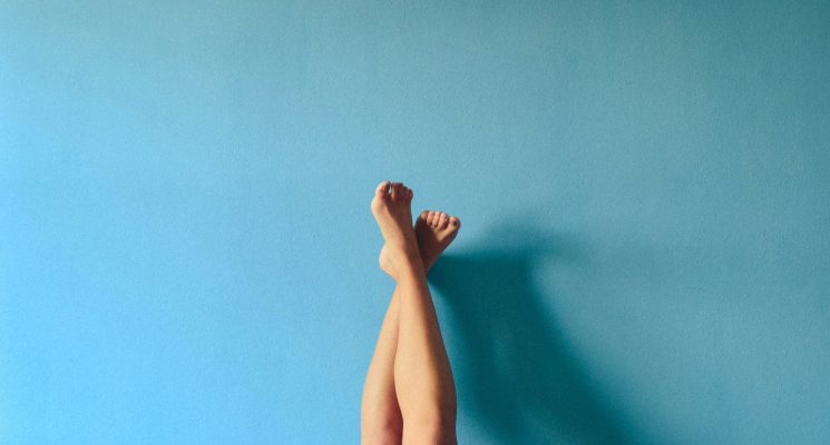 Legs crossed on blue wall