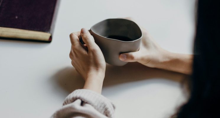 Person sitting at table with coffee with another person